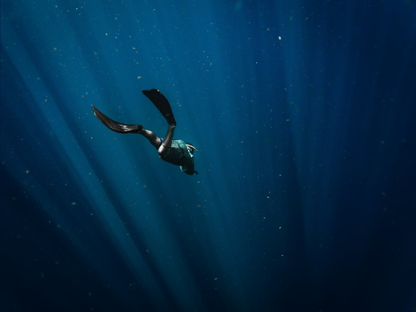 A freediver descending into deep blue water