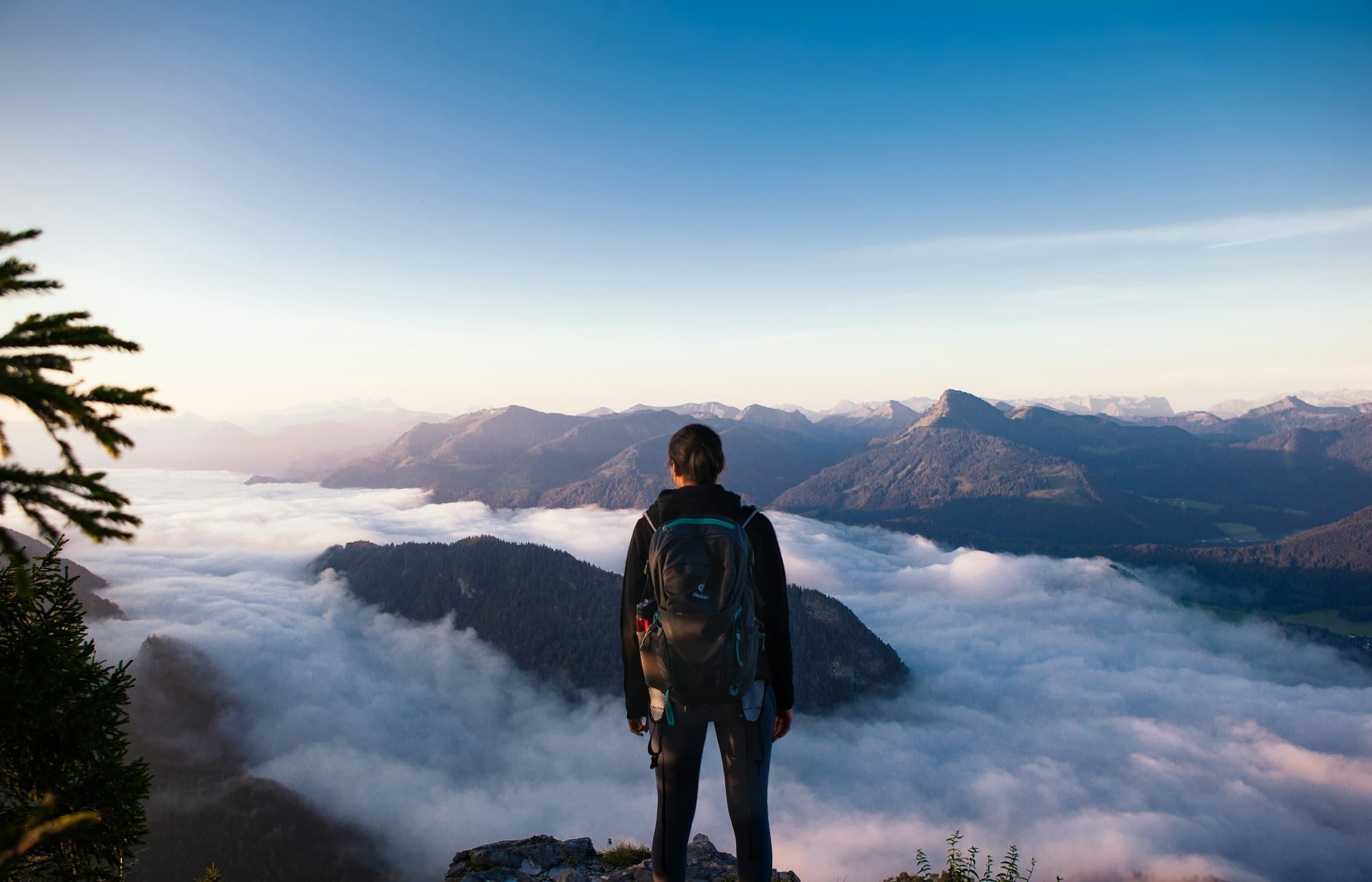 A lone figure on a rocky ridge looking out over distant peaks in fading light