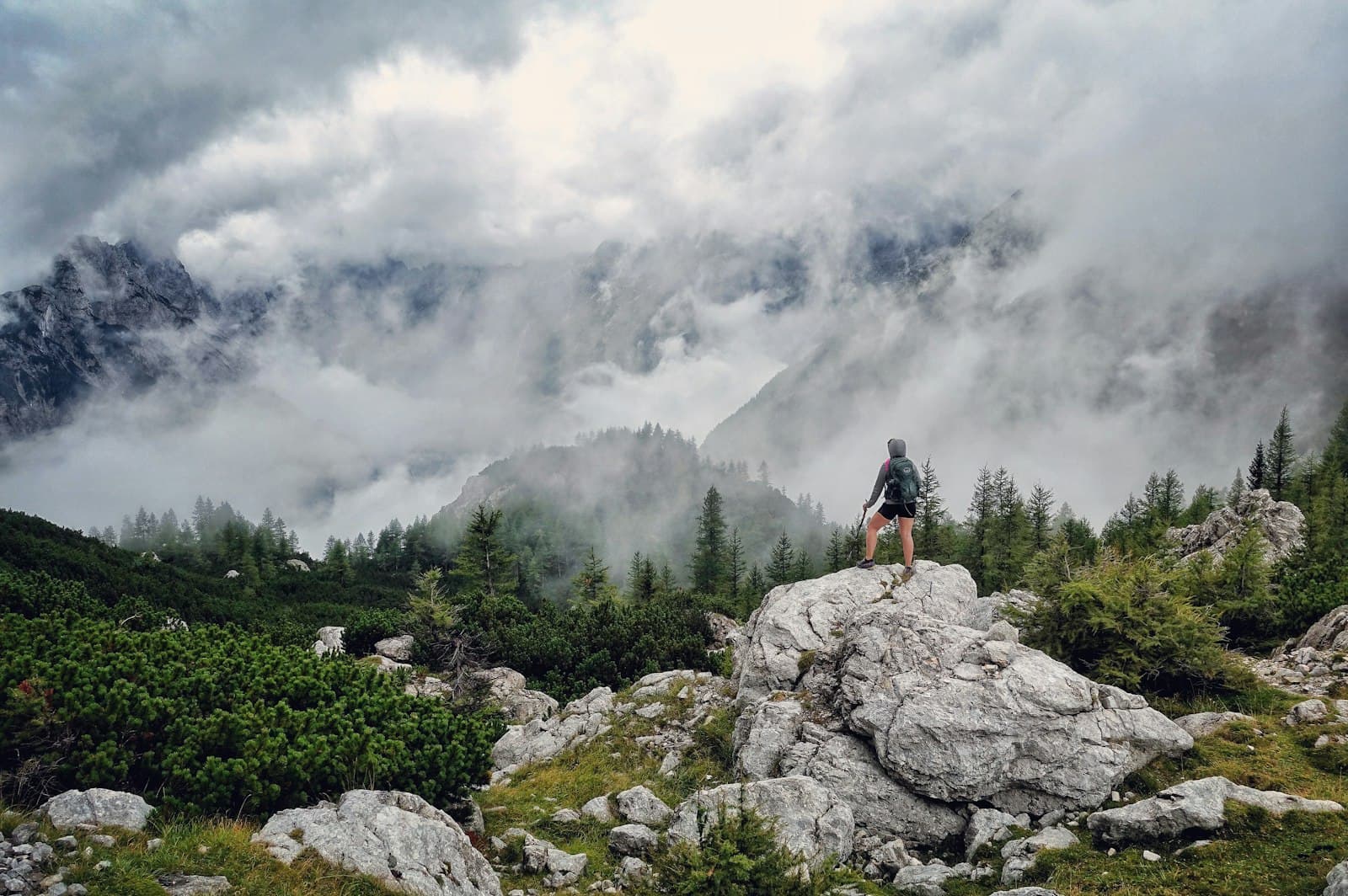 A hiker standing on a boulder above a mountain range